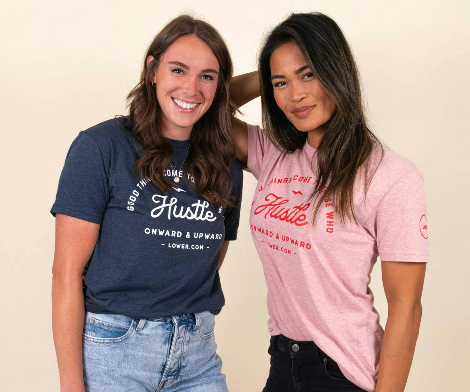 Two girls wear matching shirts that say "hustle," one blue shirt, one pink 