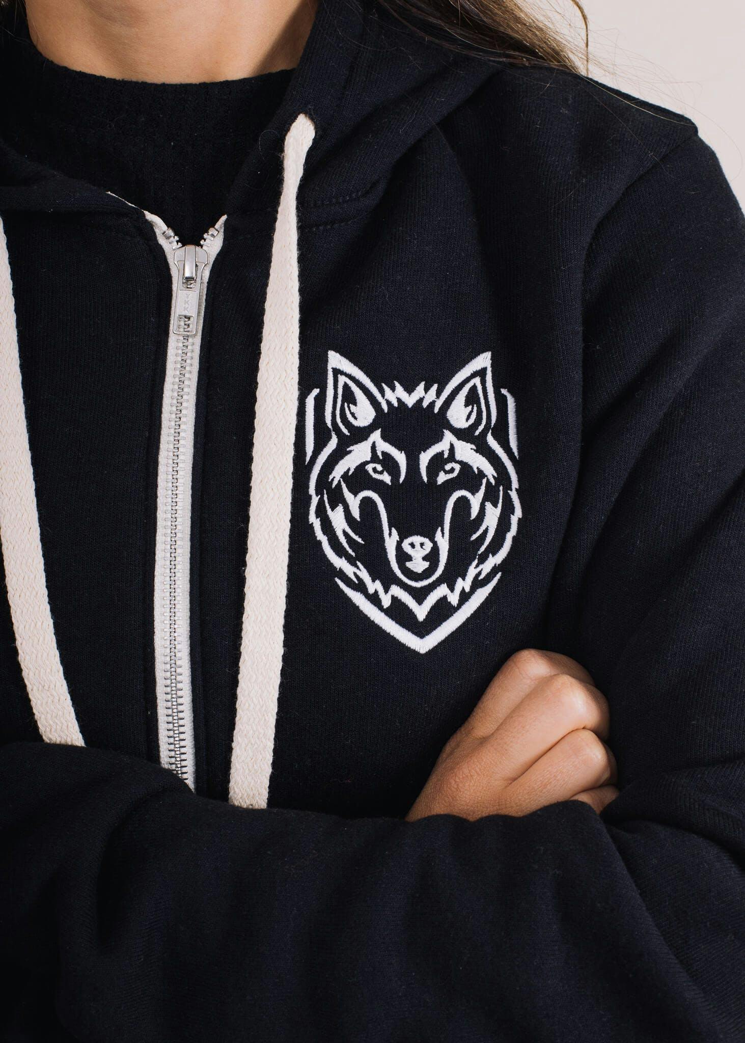 A black zip up hoodie with a white wolf embroidered on it 