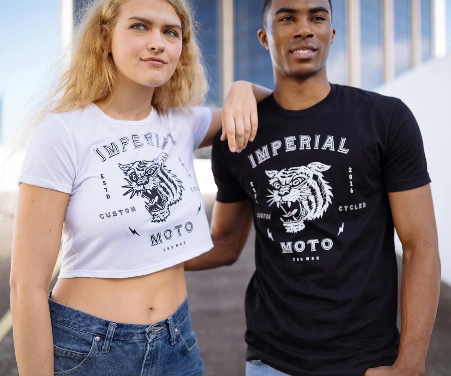 A woman wears a white crop top and a man wears a black t-shirt, both with a tiger design and the words "imperial moto" 